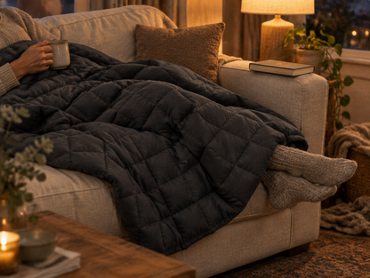Frau mit Tee unter der Gewichtsdecke auf dem Sofa